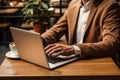 Close-up of businessman in suit typing on laptop and sitting at table in cafe. Online working. Coffee shop coworking space. Royalty Free Stock Photo