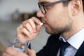 Close up businessman taking meds, holding glass of water