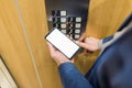 Man hands holding blank screen mobile phone while using elevator control panel