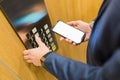 Man hands holding blank screen mobile phone while using elevator control panel Royalty Free Stock Photo