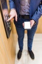 Close up of businessman using blank screen smartphone and pressing elevator button. Business and office building meeting concept Royalty Free Stock Photo