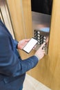 Close up of businessman using blank screen smartphone and pressing elevator button. Business and office building meeting concept Royalty Free Stock Photo