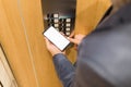 Close up of businessman using blank screen smartphone and pressing elevator button