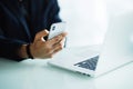 Close up of businessman using mobile phone and laptop computer on desk in modern office Royalty Free Stock Photo