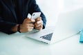 Close up of businessman using mobile phone and laptop computer on desk in modern office Royalty Free Stock Photo