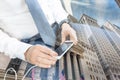 Close up of businessman using mobile smart phone in taxi against New York stock exchange reflection.