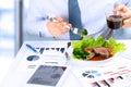 Close-up of businessman working on marketing strategy during business lunch, eating juicy club steak