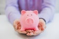 Close-up Of Businessman's Hand Holding Piggybank Over White Background.