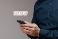 Close-up, the businessman& x27;s hands holding the phone and the Startup text. Concept of financing business, technology and