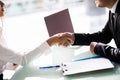 Close-up Of Businesspeople Shaking Hands At Office Desk after sign of contract