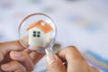 Close-up Of A Businessperson`s Hand Looking At House Model Through Magnifying Glass, House searching concept with a magnifying Royalty Free Stock Photo