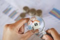 Close-up Of A Businessperson`s Hand Looking At House Model Through Magnifying Glass, House searching concept with a magnifying Royalty Free Stock Photo