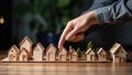 Close-up Of Businessperson\'s Hand Protecting Wooden House Model On Table