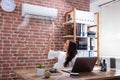 Businesswoman Adjusting The Temperature Of Air Conditioner Royalty Free Stock Photo