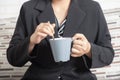 Close-up businesswoman hand holding a mug of coffee and stirring
