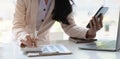 Close-up of a businesswoman hand holding a pen and smartphone using a calculator to calculate statistics analysis at the office Royalty Free Stock Photo