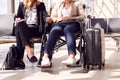 Close Up Of Businesswoman Sitting In Airport Departure With Female Colleague In Wheelchair