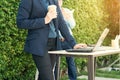 Close-up of businesswoman typing documents on keyboard of laptop hold cup of coffee and business people working at background. Royalty Free Stock Photo