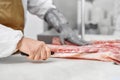 Close up of butcher hands in gloves cutting meat with knife. Royalty Free Stock Photo