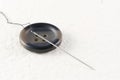 Close up of a button with needle and thread on a white background Royalty Free Stock Photo