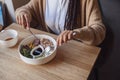 Close-up of a cafe visitor holding cutlery and tasting delicious healthy food served in white ceramic bowl in restaurant