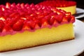 Close up of cake with soft biscuit base, layer of strawberry cream and fresh quartered strawberries with sugar topping, made with Royalty Free Stock Photo