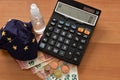 Close-up of a calculator, euro bills and diy facemask, designed as an Europian Union flag. Royalty Free Stock Photo