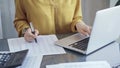 Close-up of a calculator with a female professional working with spreadsheets and a laptop on the background. Audit and