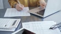 Close-up of a calculator with a female professional working with spreadsheets and a laptop on the background. Audit and