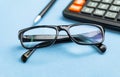 Close up of pen and glasses on blue background for mockup design modern lifestyle stationary concept. Blue office table