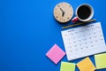 Close up of calendar, coffee, clock and pencil on the blue table