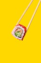 Close up California Roll with salmon fish and cucumber on chopsticks on yellow background Royalty Free Stock Photo