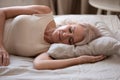 Calm senior woman sleeping in comfortable bed at home