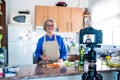 Close up of camera filming a mature woman or senior cooking and doing live or video for her social networks and medias -