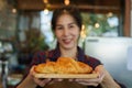 Close-up camera in front bakery owner handing out tray with small croissants, slowly backed away at reasonable distance, woman