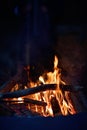 Close-up of a campfire. Fire burning brightly with a big yellow and orange flame in the dark. Firewood and logs burning to ember Royalty Free Stock Photo