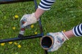 Close-up of a can of black paint in hands in construction gloves, painting an iron staircase black with a brush, outdoors. Royalty Free Stock Photo