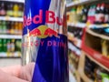 close-up of a can of energy drink with caffeine and taurine Red Bull in hand against the background of shelves with