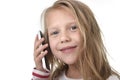 Close up candid portrait of beautiful female child with blond hair and blue eyes using mobile phone talking happy Royalty Free Stock Photo