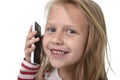 Close up candid portrait of beautiful female child with blond hair and blue eyes using mobile phone talking happy