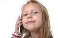 Close up candid portrait of beautiful female child with blond hair and blue eyes using mobile phone talking happy