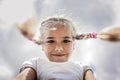 Close-up candid portrait of cute girl with two funny braids taken up at the sky from the ground