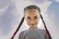 Close-up candid portrait of cute girl with two funny braids taken up at the sky from the ground