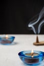 Close-up of candle with blue glass, burning incense, selective focus, on white table, black background, Royalty Free Stock Photo