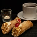 Close-up of cannoli on black stone slab.