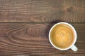 Close-up of Cappuccino or latte coffee with milk foam in white ceramic cup coffee on natural wood texture background. top view Royalty Free Stock Photo