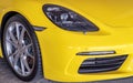 Close-up of Car Headlights and Car Wheel of Yellow Porsche Sports Car parked in the parking lot