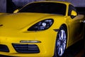 Close-up of Car Headlights and Car wheel of Yellow porsche sports car parked in the parking lot