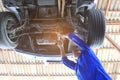 Close-up of car mechanic working under car in auto repair service