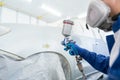 Close up of Car Painter in protective clothes and mask painting automobile bumper with metallic paint and varnish in chamber Royalty Free Stock Photo